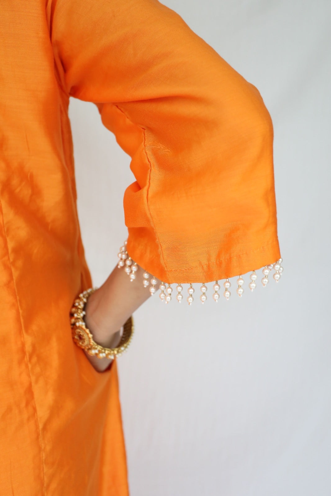 Orange chanderi kurta set with a hand embroidered yoke, intricate pearl detailing on the sleeves with an embellished scallop dupatta