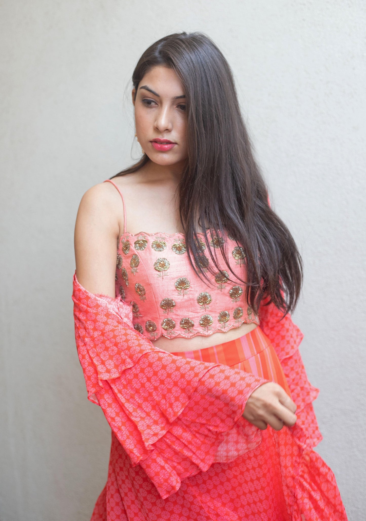 Hand embroidered pink blouse with a striped pant and geomtric floral ruffle cape