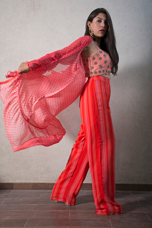 Hand embroidered pink blouse with a striped pant and geomtric floral ruffle cape