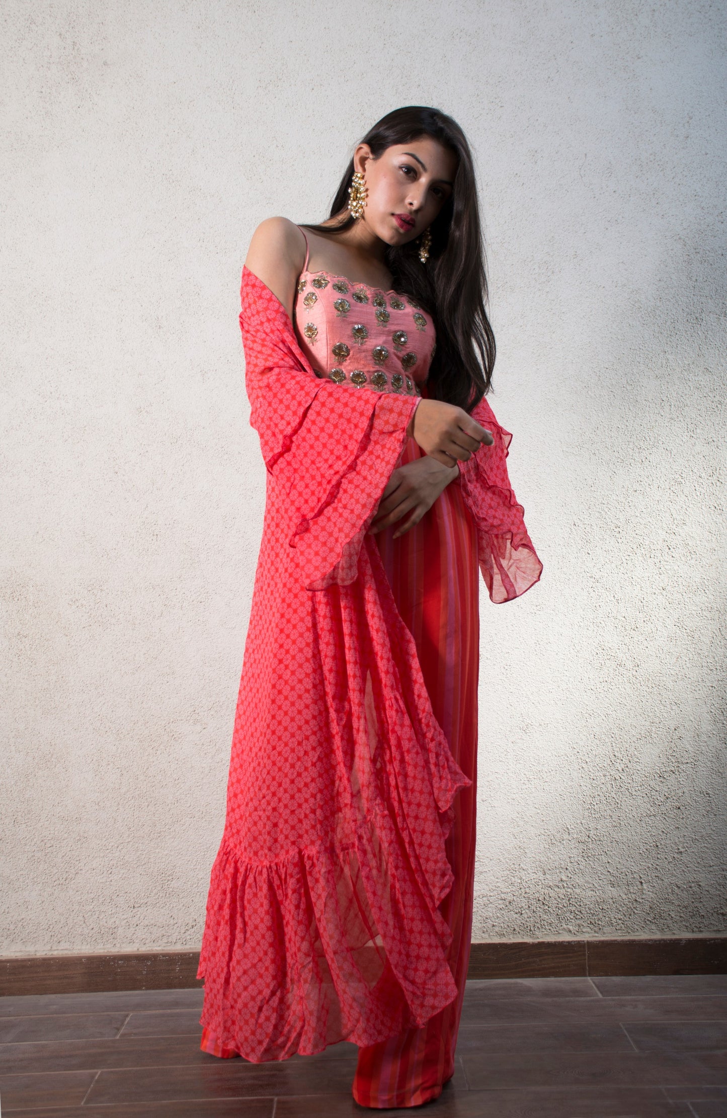 Hand embroidered pink blouse with a striped pant and geomtric floral ruffle cape