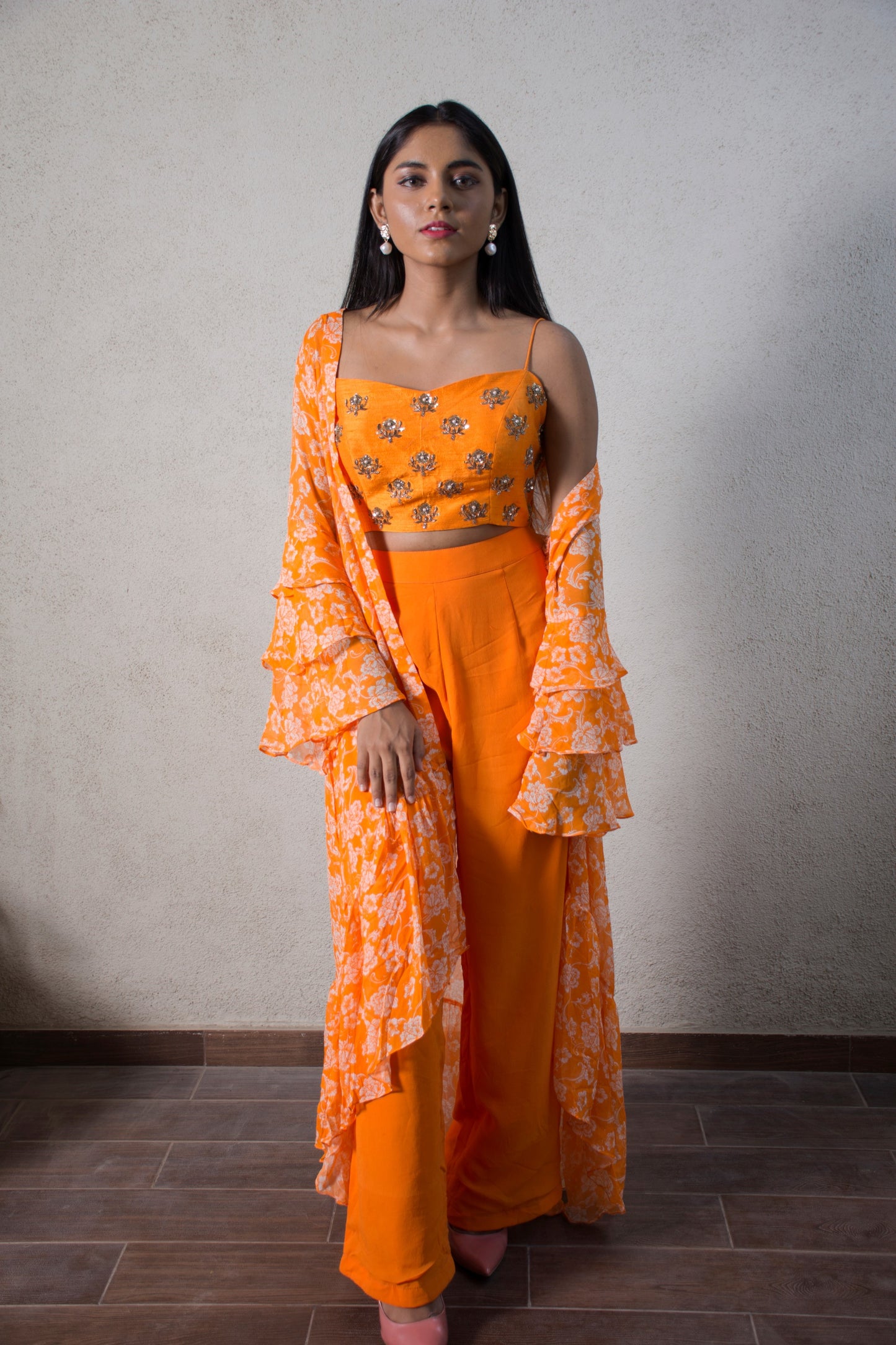 Hand embroidered orange blouse with a high waisted straight pant and floral ruffle cape