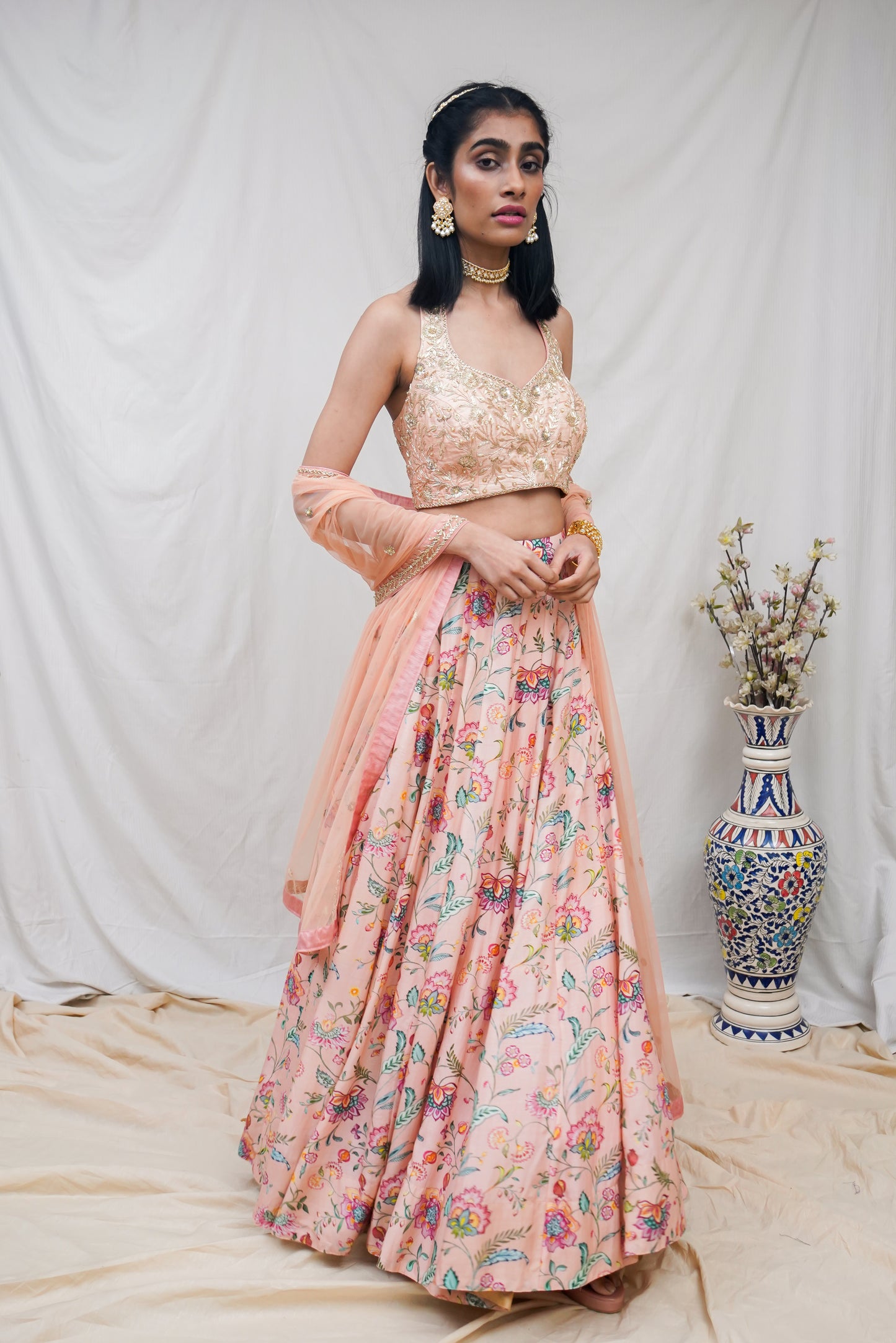 Hand embroidered peach halter blouse and dupatta with a high waisted floral printed lehenga