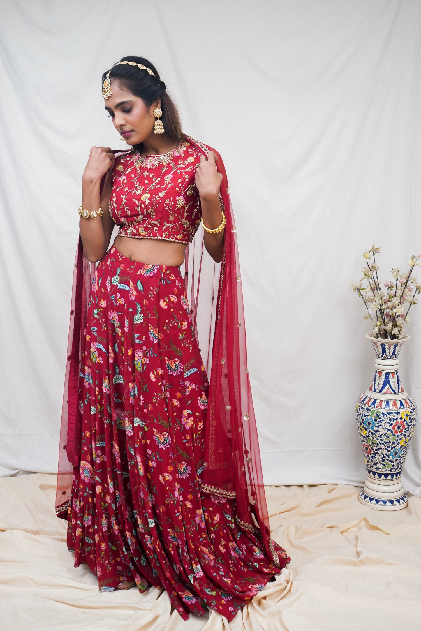 Hand embroidered red sleeveless blouse and dupatta with a high waisted floral printed lehenga