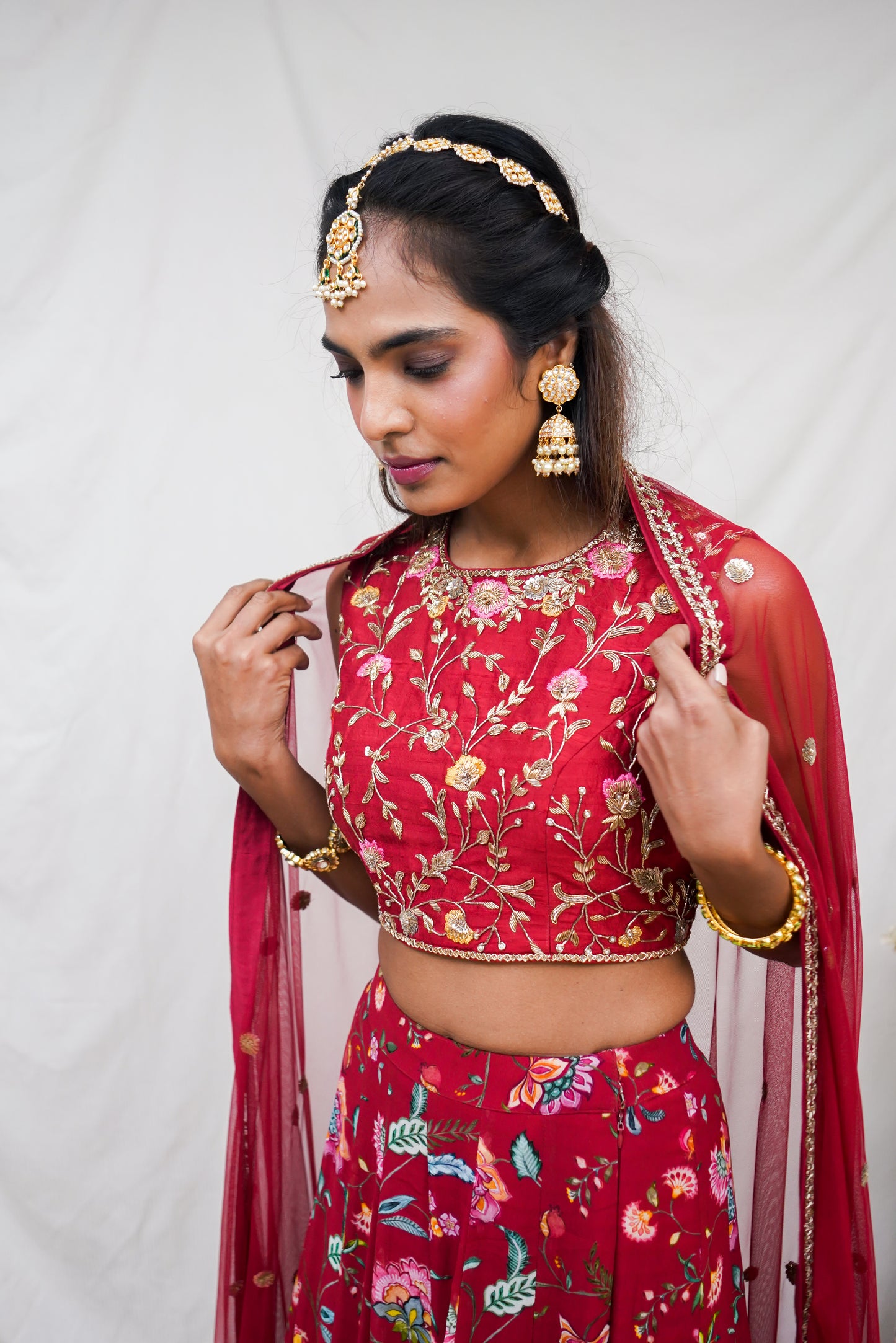 Hand embroidered red sleeveless blouse and dupatta with a high waisted floral printed lehenga