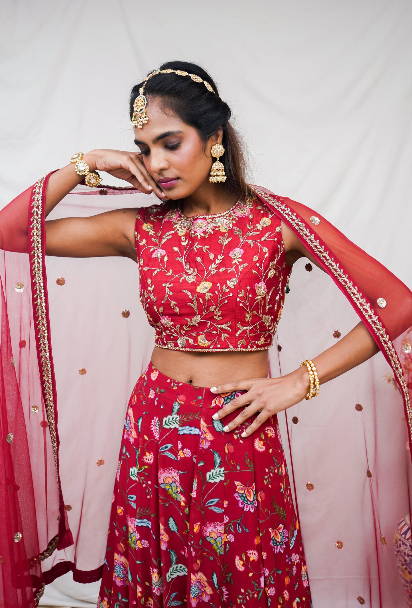 Hand embroidered red sleeveless blouse and dupatta with a high waisted floral printed lehenga