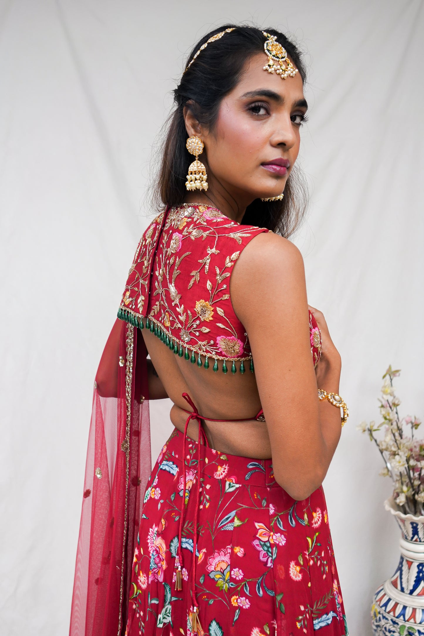 Hand embroidered red sleeveless blouse and dupatta with a high waisted floral printed lehenga