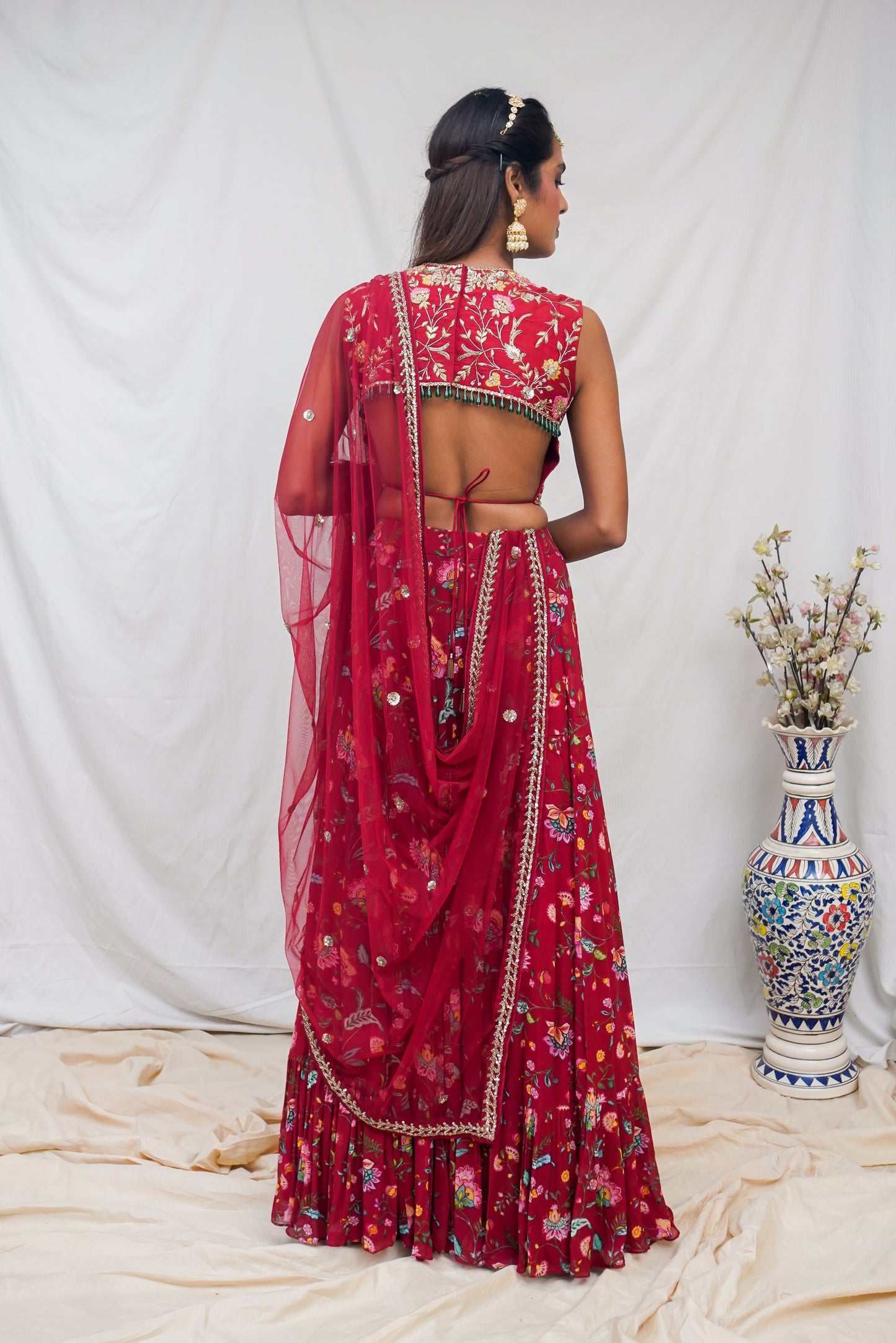 Hand embroidered red sleeveless blouse and dupatta with a high waisted floral printed lehenga