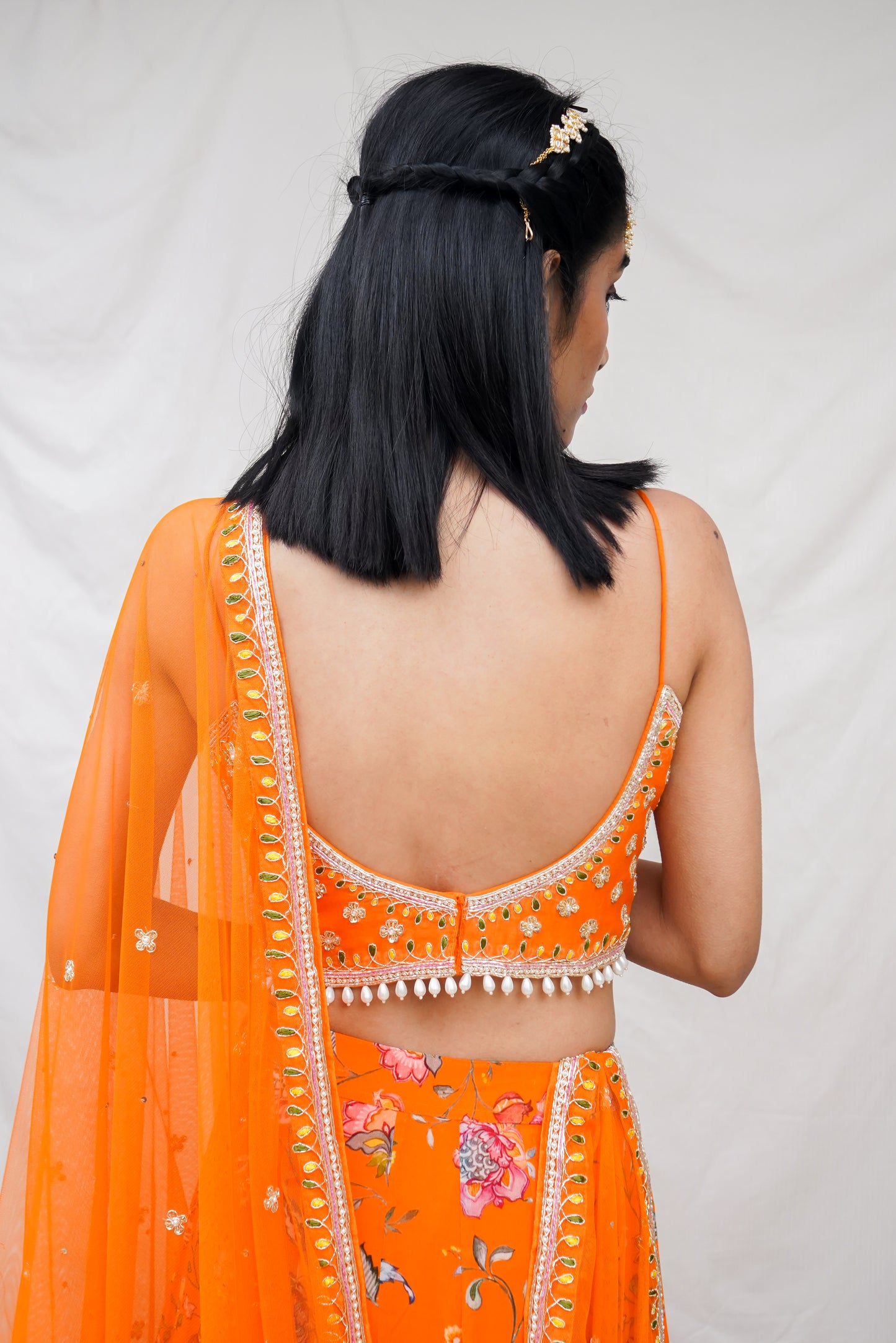 Hand embroidered orange wrap blouse and dupatta with a high waisted floral printed lehenga