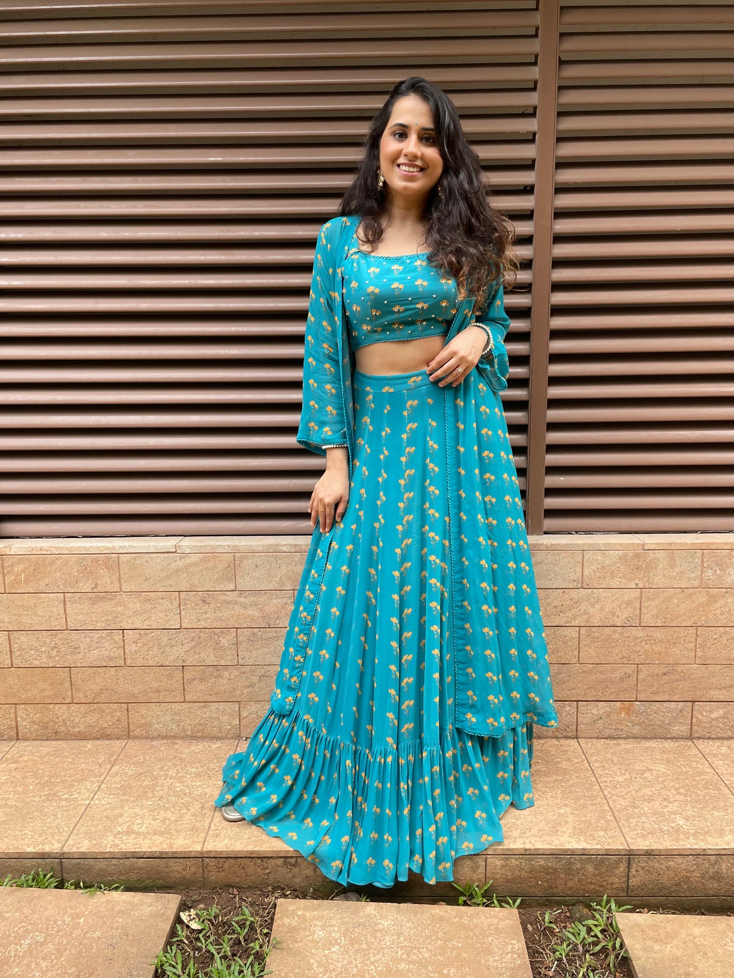 Peacock blue floral printed lehenga with an intricate hand embroidered highlighted blouse and cape